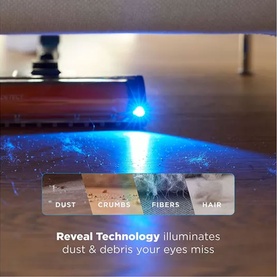Shark PowerDetect Speed Cordless Vacuum with blue Reveal Technology light illuminating dust, crumbs, fibres and hair on hard floor.