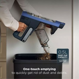 Shark PowerDetect Speed Cordless Vacuum being emptied into a bin, showing 0.5L dust cup capacity with debris visible