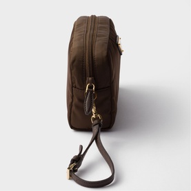Dark brown nylon cosmetics bag with gold-tone zip hardware and detachable brown leather wrist strap, shown from side angle