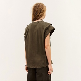 Model wearing Bash brown sleeveless T-shirt with extended shoulder detail, back view, styled with dark wide-leg trousers