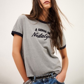 Model wearing Bash grey ringer T-shirt with navy trim and "A Sense of Nostalgia" slogan print, styled with denim jeans and belt.