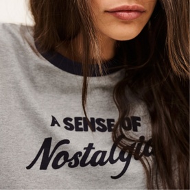 Model wearing Bash grey ringer-style sweatshirt with navy trim and "A Sense of Nostalgia" slogan print