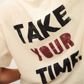 Bash cream T-shirt with distressed black and red "Take Your Time" slogan print, close-up detail shot