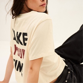 Model wearing Bash cream T-shirt with bold graphic back print, styled with black leather jacket and trousers.