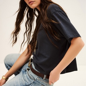 Model wearing Bash blue oversized short-sleeve T-shirt with light-wash jeans and brown leather belt with gold buckle.