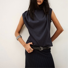 Model wearing Bash blue sleeveless satin high-neck top, styled with a ribbed midi skirt and black leather belt.