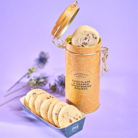 Cartwright & Butler Chocolate & Orange Shortbread Rounds in gold clip-top tin, with biscuits displayed in open tray on purple background.