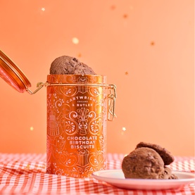 Cartwright & Butler Chocolate Birthday Biscuits in orange decorative clip-top tin, with chocolate biscuits on a white plate alongside.