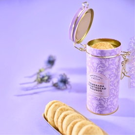 Cartwright & Butler Demerara Shortbread Rounds in open lilac and gold tin, with shortbread rounds fanned out alongside dried flowers.