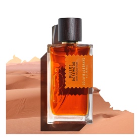 Goldfield & Banks Desert Rosewood EDP in amber glass bottle with dark cap, set against a sandy desert backdrop