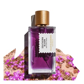 Goldfield & Banks Southern Bloom EDP in purple glass bottle with wooden cap, surrounded by pink desert wildflowers