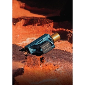 Goldfield & Banks Tales Of Amber Parfum in deep teal bottle with gold cap, styled on russet rock surface