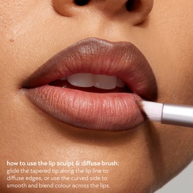 Model with Kylie Cosmetics Lip Sculpt & Diffuse Brush applied along lip line, demonstrating blending technique on full lips.