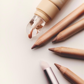 Kylie Cosmetics beauty brushes and nude-tone lip liner pencils in warm brown shades, arranged on white surface