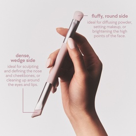 Kylie Cosmetics dual-ended makeup brush with fluffy round side and dense wedge side, held in hand against pink background