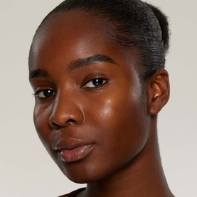 Model wearing Kylie Cosmetics Makeup Primer, showcasing a smooth, radiant, even complexion finish on deep skin tone.