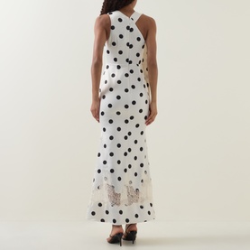 Model wearing Lavish Alice black and white polka dot maxi dress, halterneck, lace hem detail, back view