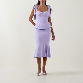 Model wearing Lavish Alice Lilac Dress with bow shoulder straps, sweetheart neckline, peplum waist and fluted midi skirt