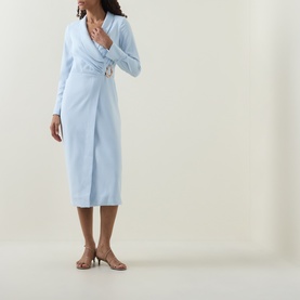Model wearing Lavish Alice blue long-sleeve wrap midi dress with gold buckle detail, styled with nude heeled mules.