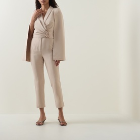 Model wearing Lavish Alice Sand jumpsuit with cape detail, styled with strappy flat sandals