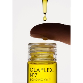Olaplex No.7 Bonding Oil dropper bottle with a drop of golden oil falling from a fingertip above the open cap