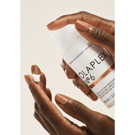 Olaplex The Healthy Hair Discovery Set, hand holding No.6 Bond Smoother cream tube against neutral background