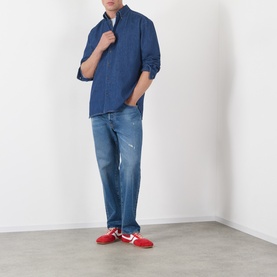 Model wearing A.P.C. washed indigo cotton casual shirt, styled with light blue distressed jeans and red trainers.