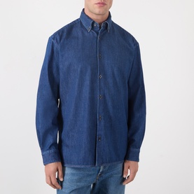 Model wearing A.P.C. washed indigo cotton denim casual shirt with button-down collar, styled with blue jeans.