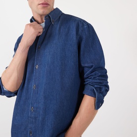 Model wearing A.P.C. casual shirt in washed indigo denim, button-down collar, long sleeves, chest shown close-up