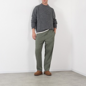 Model wearing A.P.C. heathered anthracite crew neck knit, styled with olive trousers and tan suede loafers.