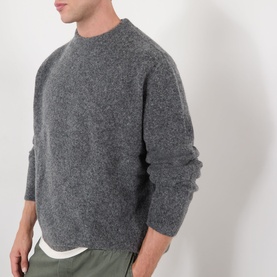 Model wearing A.P.C. heathered anthracite crew neck knit in wool-alpaca blend, styled with khaki trousers.