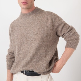 Model wearing A.P.C. taupe crew neck knit jumper in wool-alpaca blend, styled with white trousers and black belt
