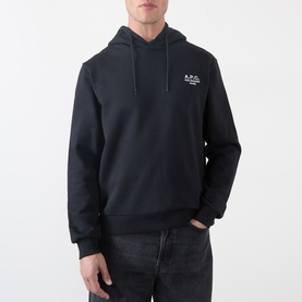 Model wearing A.P.C. black cotton hoodie with small logo print on chest, paired with dark jeans.