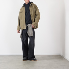 Model wearing A.P.C. black cotton hoodie, styled with olive cargo jacket and dark wide-leg trousers