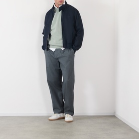 Model wearing A.P.C. Fernando Logo Sweatshirt in gray green with navy zip jacket, grey trousers and white trainers.