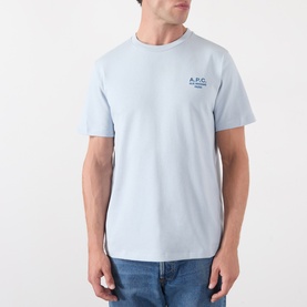 Model wearing A.P.C. light blue cotton T-shirt with small navy chest logo print, styled with blue jeans.