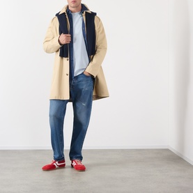 Model wearing A.P.C. Bleu Clair cotton T-shirt, styled with beige mac coat, navy gilet, blue jeans, and red trainers.
