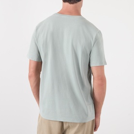 Model wearing A.P.C. gray green cotton T-shirt, rear view, styled with beige trousers