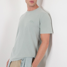 Model wearing A.P.C. gray green cotton T-shirt with tonal chest logo, styled with beige drawstring shorts.
