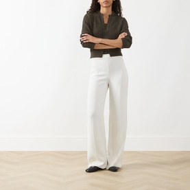 Model wearing Akris Punto olive cotton cardigan with white wide-leg trousers and black flat shoes