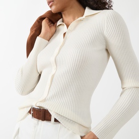 Model wearing Akris Punto cream ribbed wool cardigan with collar and button front, styled with a brown belt and white trousers