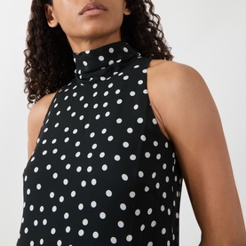 Model wearing Akris Punto black and cream polka dot sleeveless high-neck viscose dress, close-up detail view.