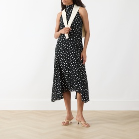 Model wearing Akris Punto black-cream polka dot midi dress with asymmetric hem, styled with a white scarf and nude heeled sandals
