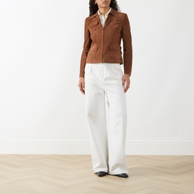 Model wearing Akris Punto hazel leather jacket with patch pockets, styled with white wide-leg trousers and black shoes.