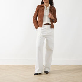 Model wearing Akris Punto hazel goat leather jacket, styled with white wide-leg trousers, cream blouse and brown belt.