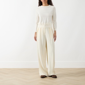 Model wearing Akris Punto cream wool knit sweater, styled with wide-leg cream trousers and dark loafers