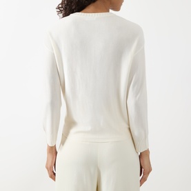 Model wearing Akris Punto cream 100% virgin wool knit sweater, back view, styled with matching cream trousers.