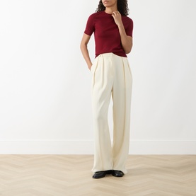 Model wearing Akris Punto Pomegranate wool knit top with cream wide-leg trousers and black loafers