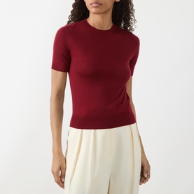 Model wearing Akris Punto pomegranate wool knit short-sleeve crew-neck top, styled with cream wide-leg trousers.