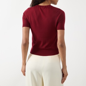 Model wearing Akris Punto pomegranate wool knit short-sleeve top, back view, styled with cream wide-leg trousers